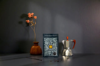 Sacchetto di Specialty Coffe Filicori Zecchini con a lato una caffettiera moka e un decoro di fiori essiccati.