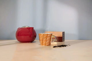Tazza di tè caldo con teiera rossa.
