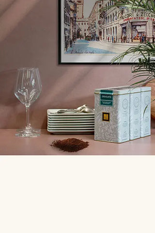 Tin cans of ground coffee, plates, cutlery and glasses. Historical picture Filicori Zecchini in the background.