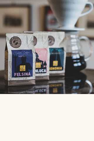 Tre sacchetti monoporzione da 34g di caffè macinato per filtro - caffettiera V60 sullo sfondo.