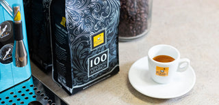 Gros plan sur un sac de café 100 Percento Arabica, avec une tasse d'expresso Filicori Zecchini.